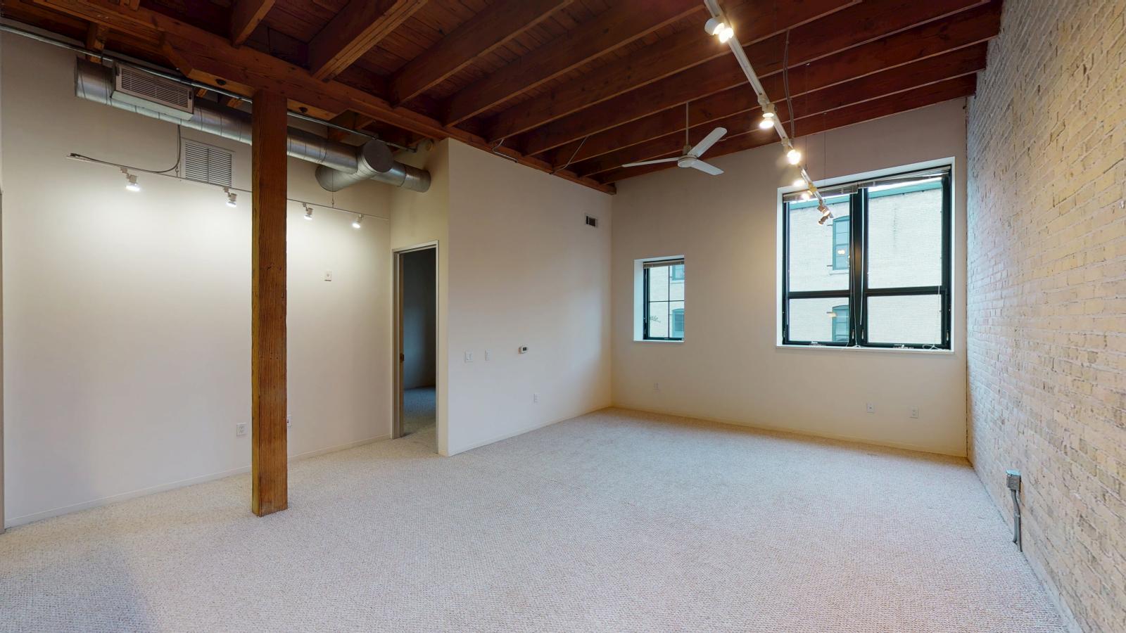 One bedroom featuring exposed brick, large windows, skylight, and soft industrial finishes at Tobacco Lofts at The Yards in downtown Madison