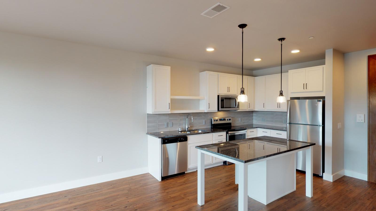 Modern kitchen in a 1722 Monroe apartment in Madison with white cabinetry, quartz countertops, and stainless steel appliances.