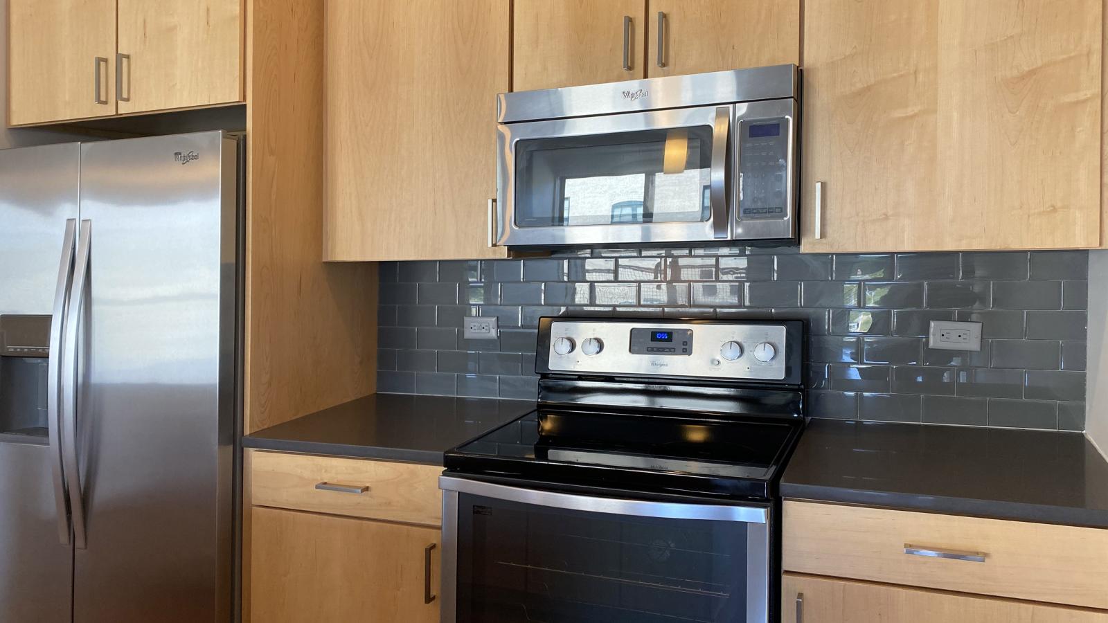 Open concept kitchen with sleek cabinetry and stainless steel appliances at SEVEN27