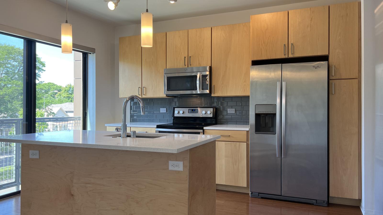Open concept kitchen with sleek cabinetry and stainless steel appliances at SEVEN27 in downtown Madison