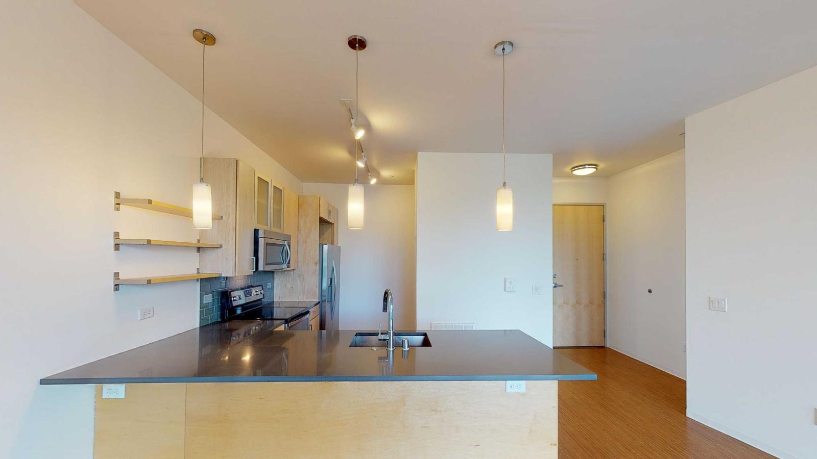 One bedroom apartment kitchen with open shelving and stainless steel appliances at SEVEN27