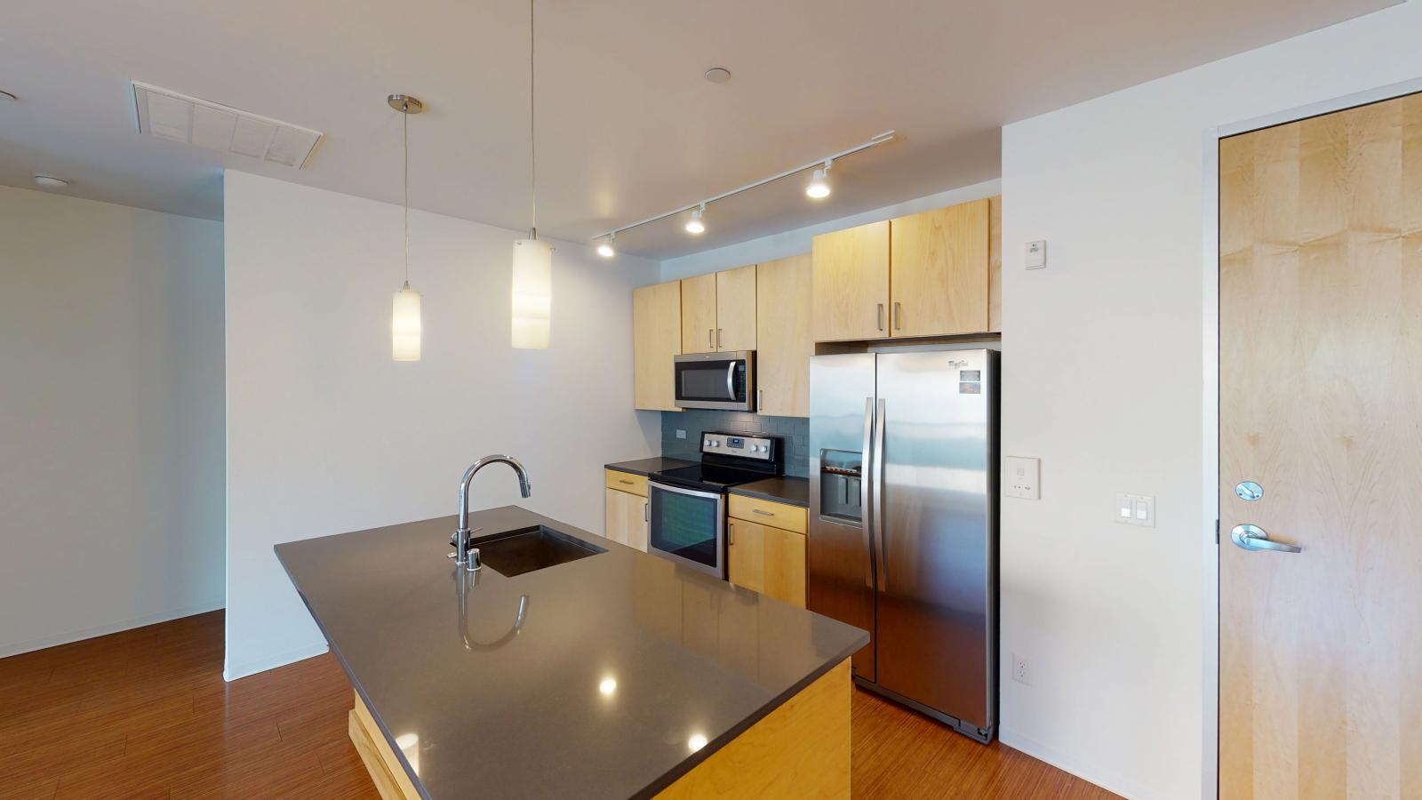 One bedroom apartment with modern kitchen with quartz countertops and stainless steel appliances at SEVEN27 in downtown Madison